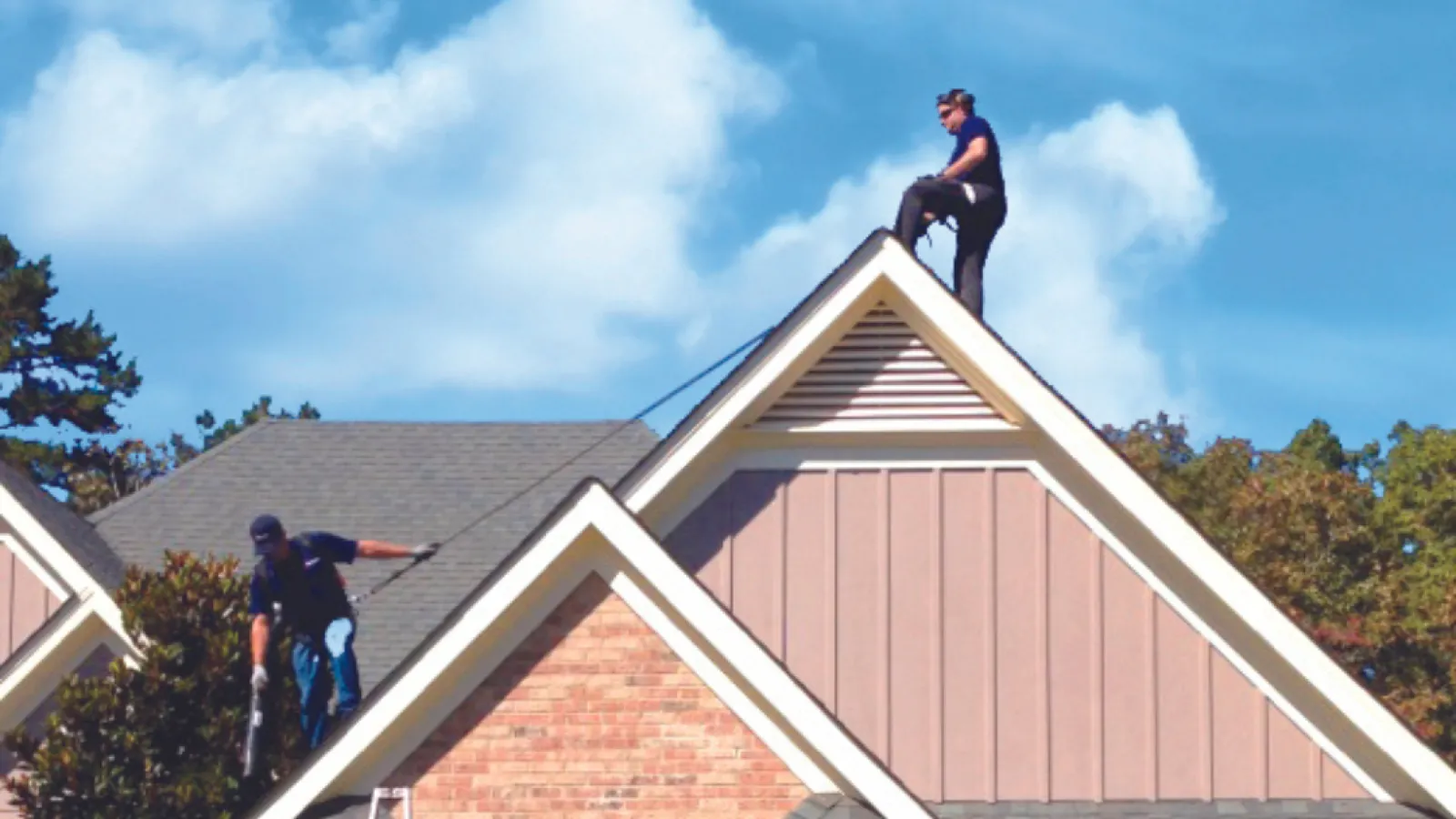 Two Team Advanced technicians on a roof cleaning gutters