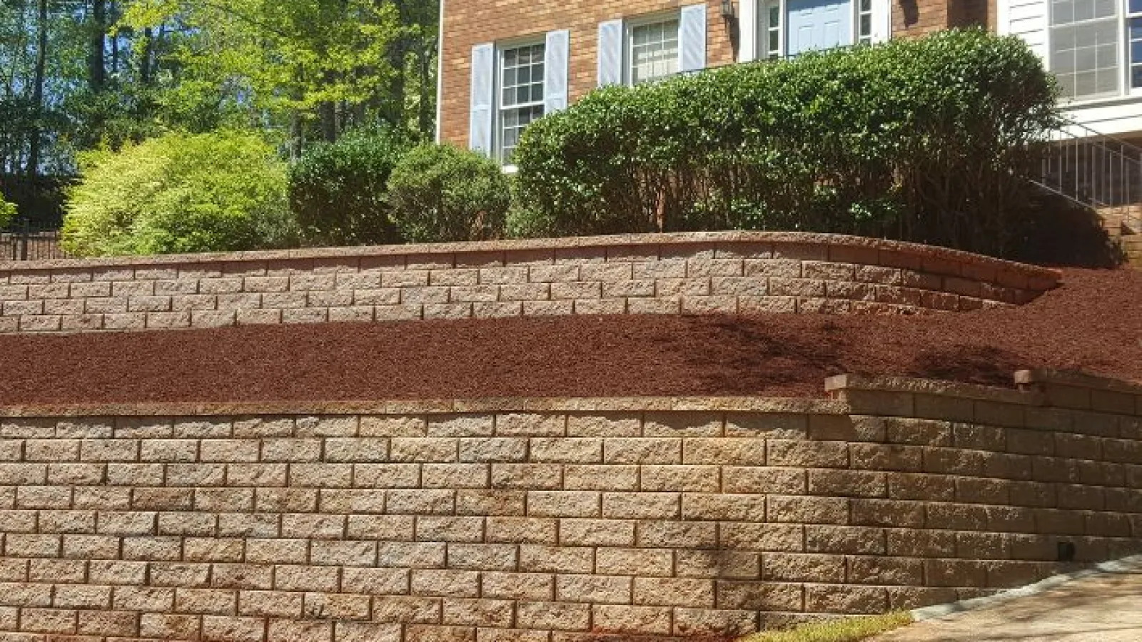 a brick wall with a brick wall and grass and trees in the background