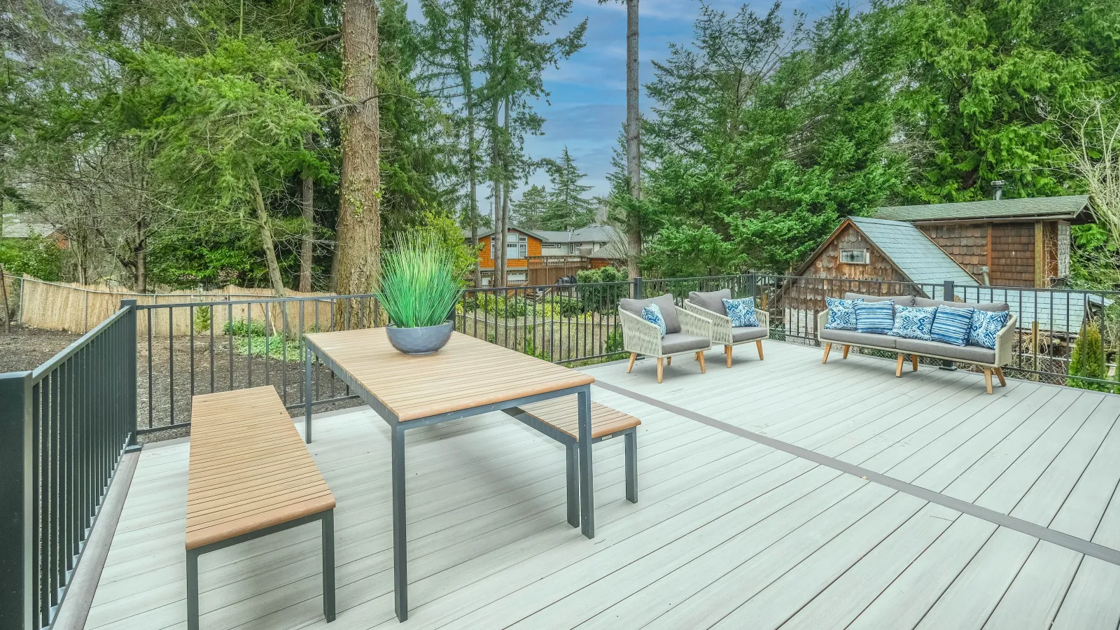 a deck with tables and chairs on it and trees in the back