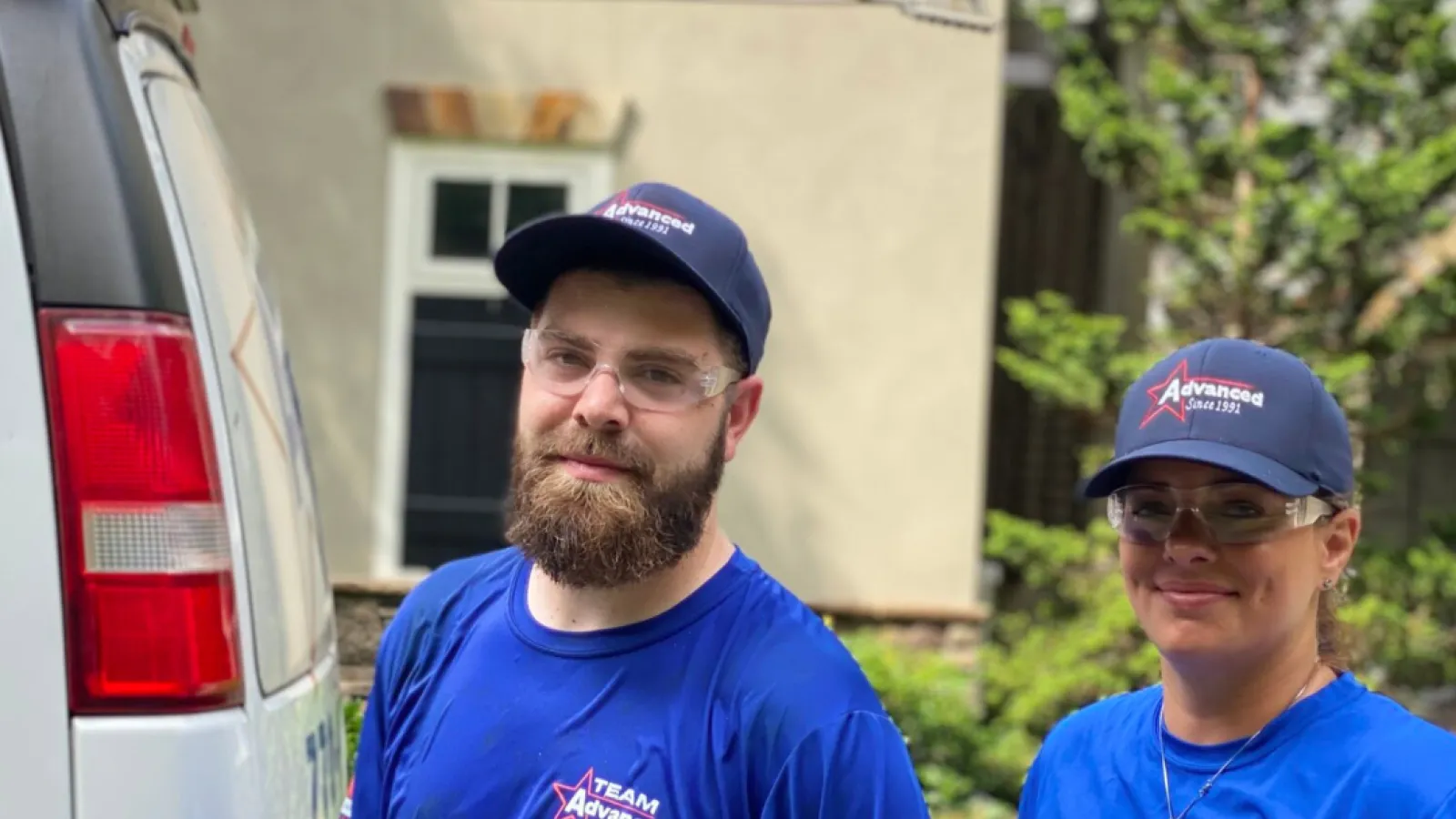 a man and a woman in blue shirts standing next to a car