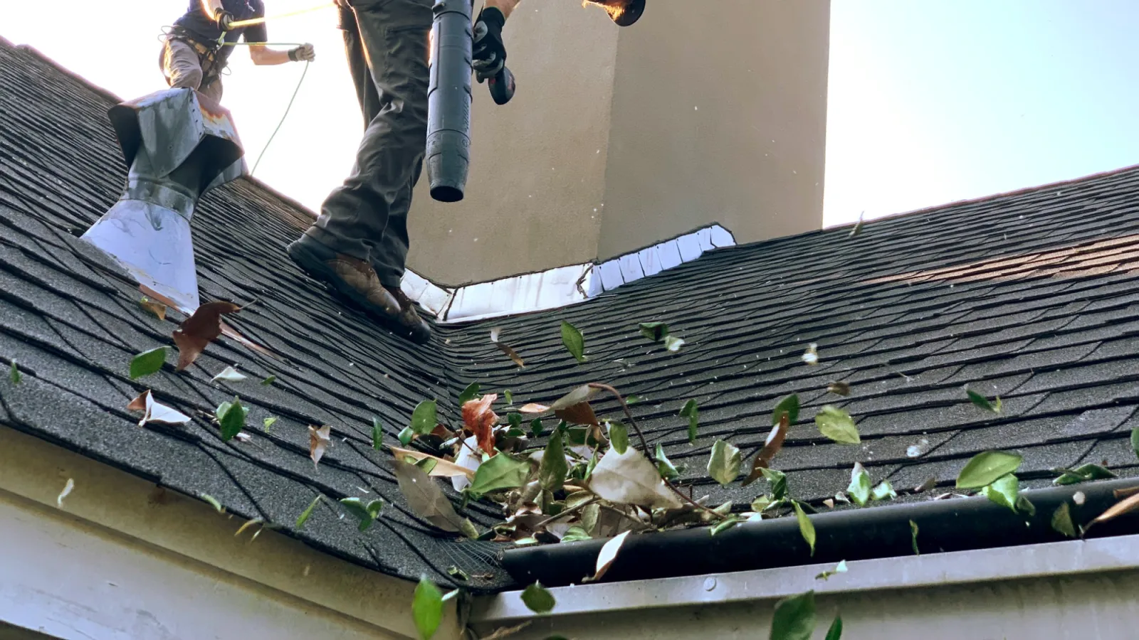 a person blowing leaves on a roof