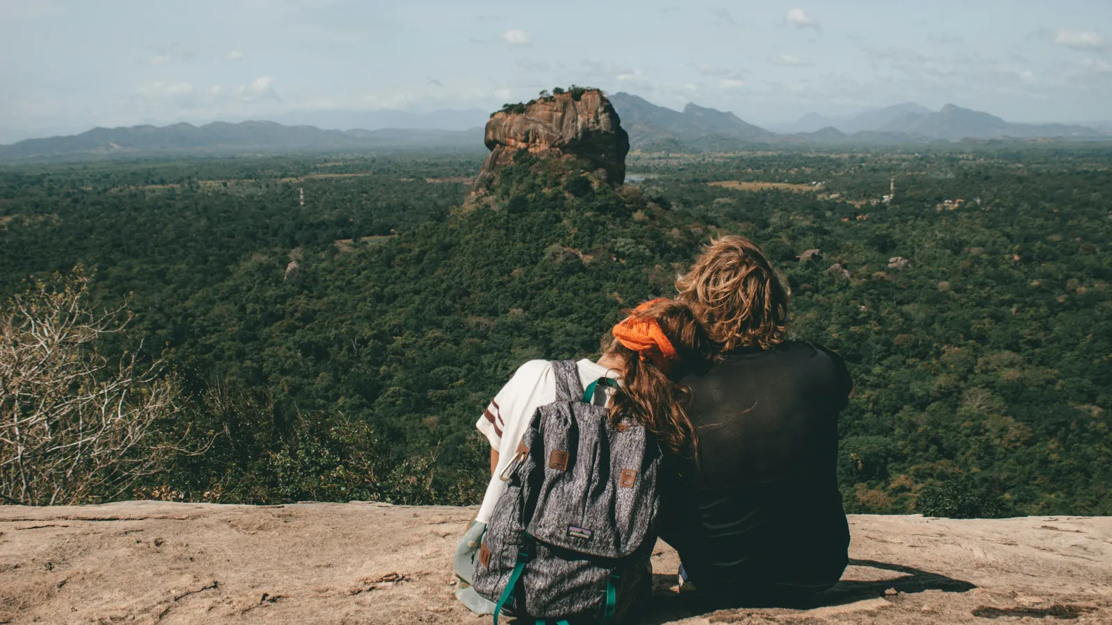 two people hugging on a hill