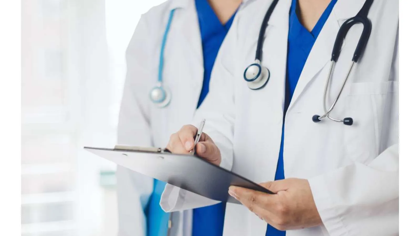 Doctors in white coats with stethoscopes reviewing medical records on a clipboard in a clinical setting