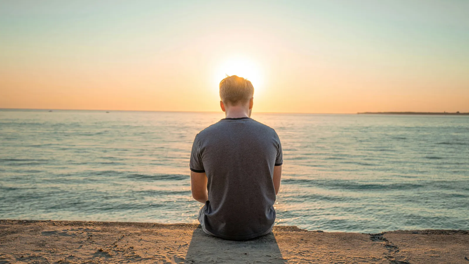 a man sitting on a beach looking at the water