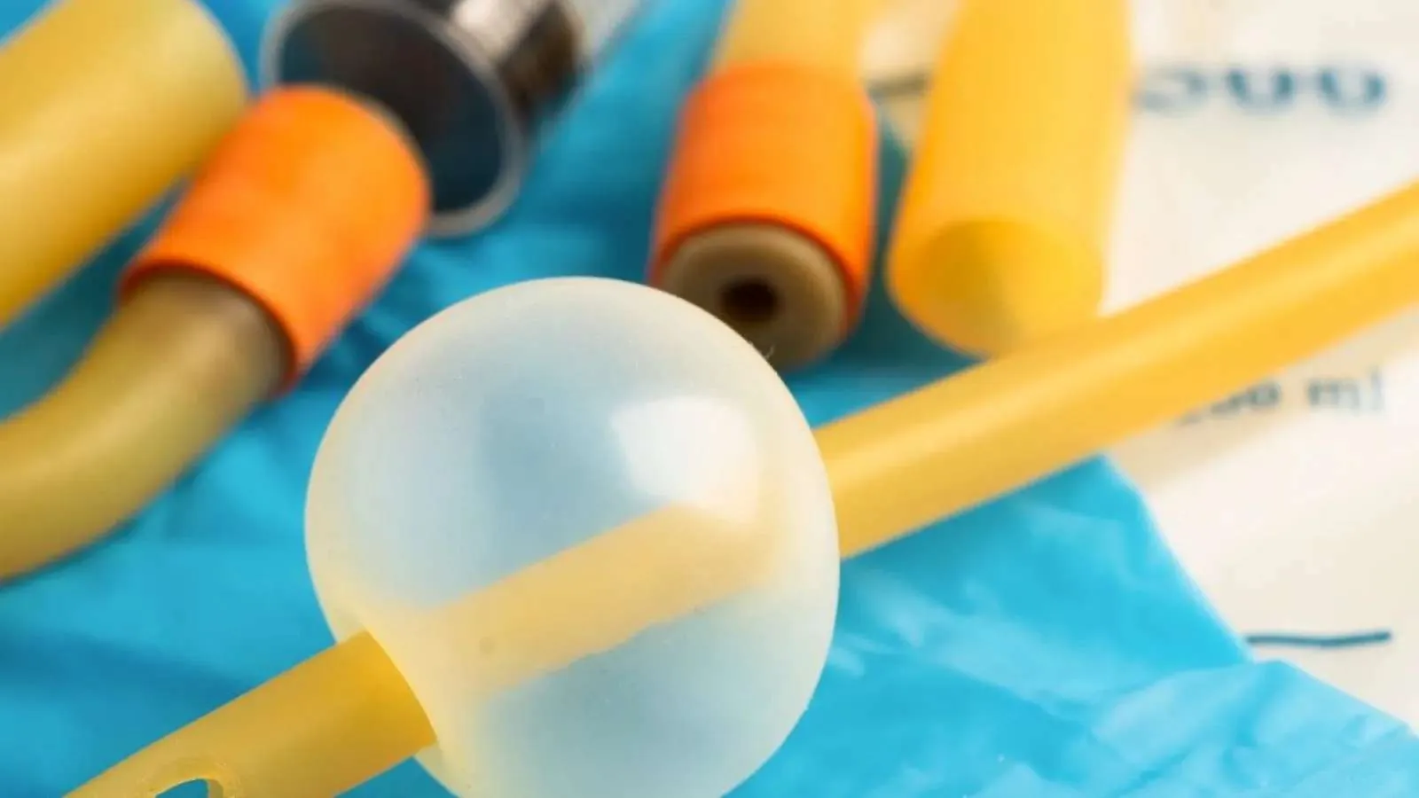 Close-up of medical equipment including catheters and a Foley catheter balloon on a blue sterile field.