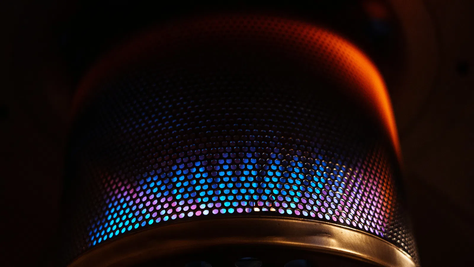 Close-up of a patio heater burner with blue and orange flames glowing through a perforated metal screen