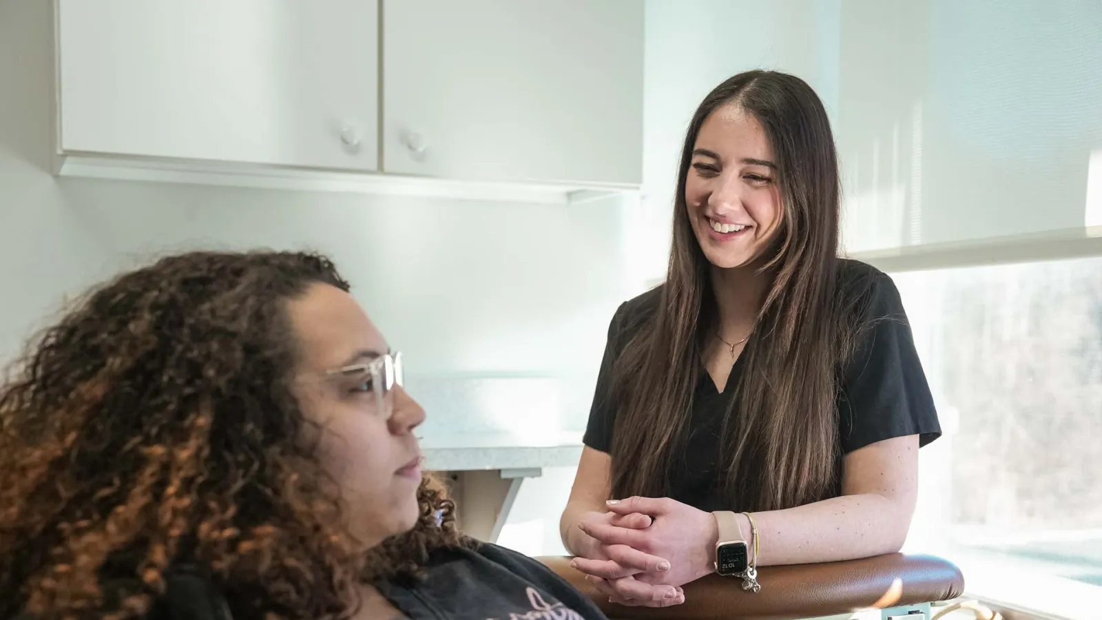 Smiling healthcare professional talking with a patient in a bright medical office during consultation.