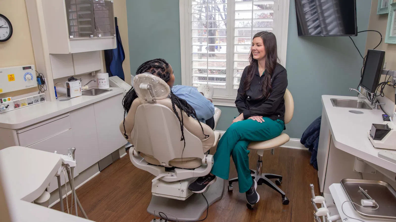 Dentist consulting with patient in a modern dental office with natural light from arched window.