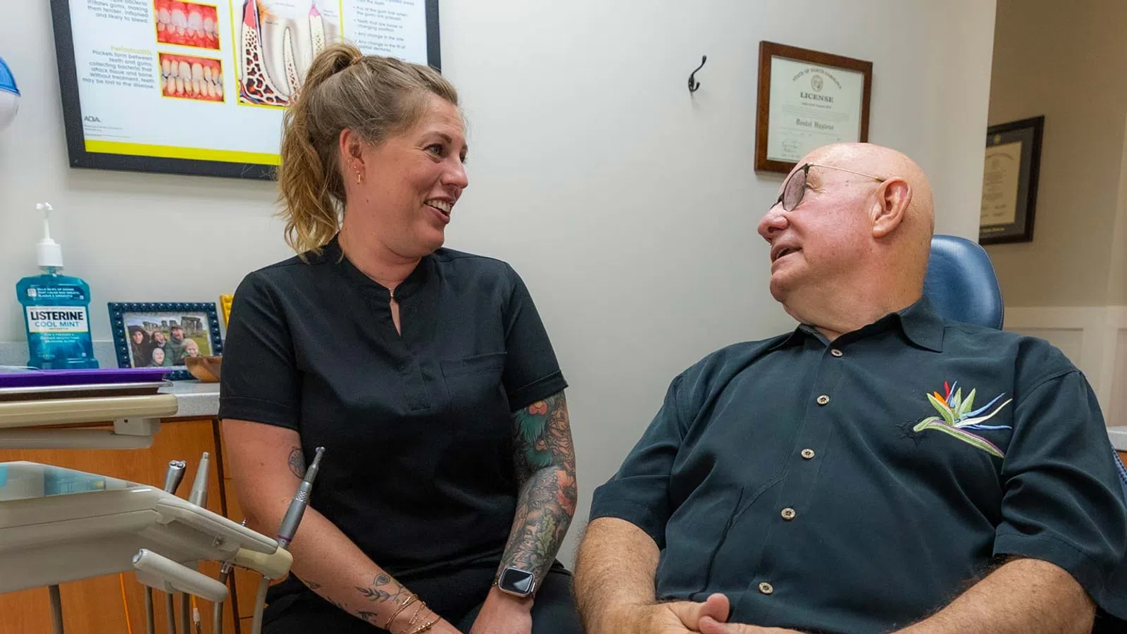Female dentist consulting with a smiling elderly male patient in a dental office setting.