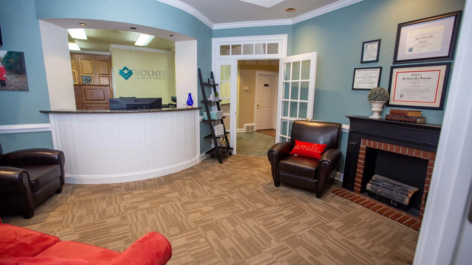 Reception area of Volner Family Dentistry with seating, front desk, certificates, and calming blue walls.