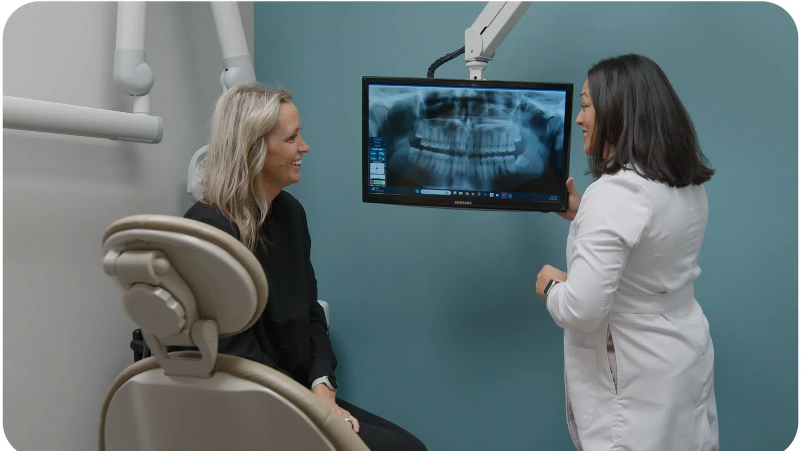 Dentist explaining dental X-ray results to a female patient in a modern clinic room.