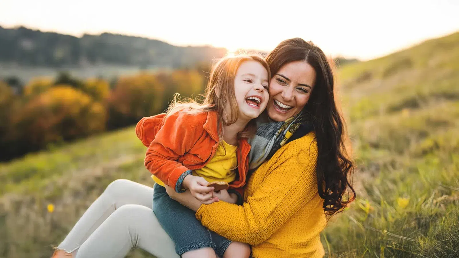 a person and a child sitting in a grassy field