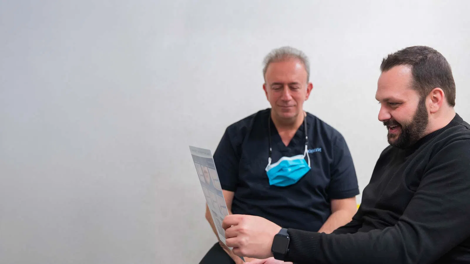Doctor consulting with a patient reviewing medical documents together in a clinical setting.
