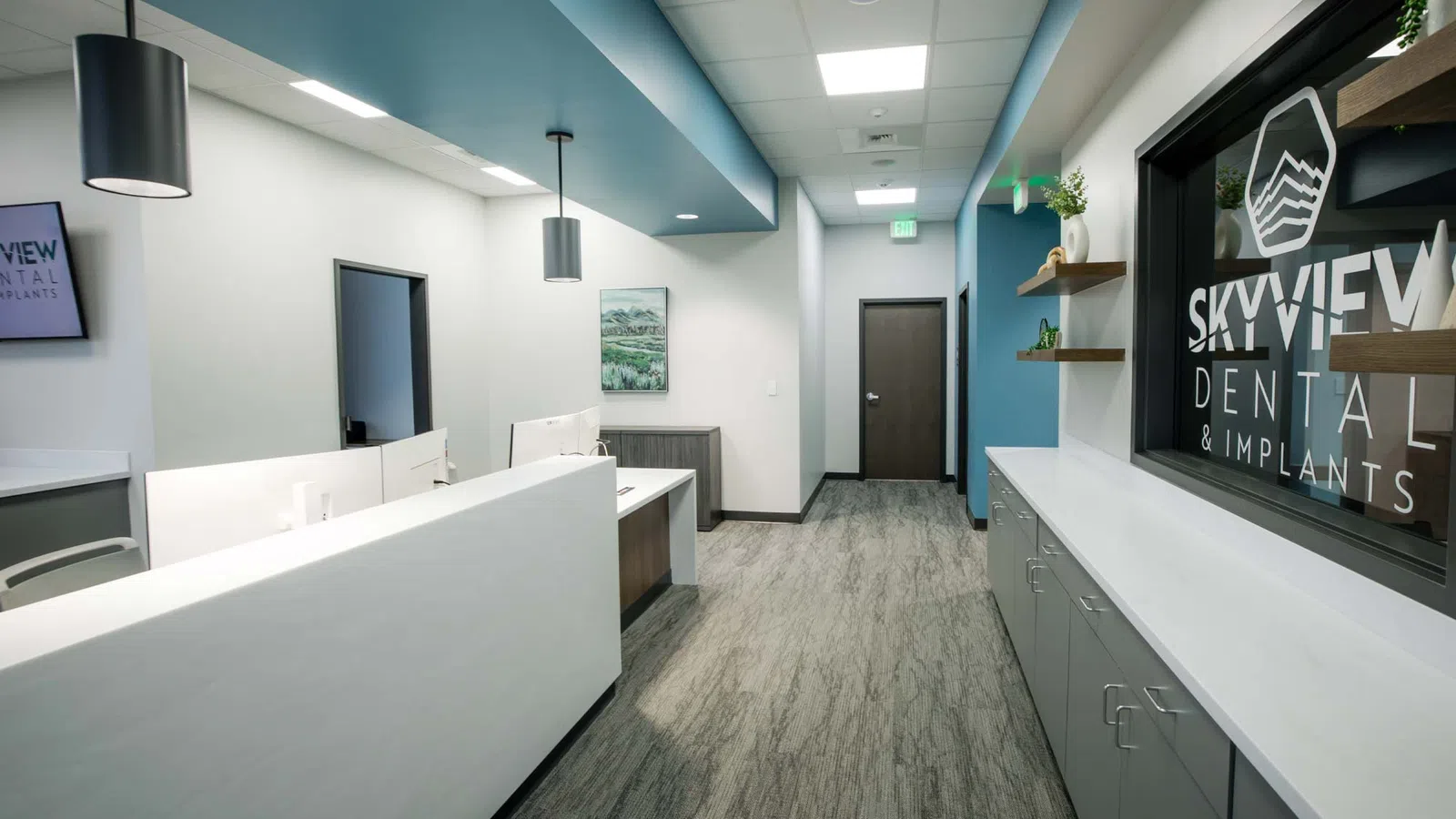 Modern dental office reception area with white desks, blue ceiling accents, and SkyView Dental signage.