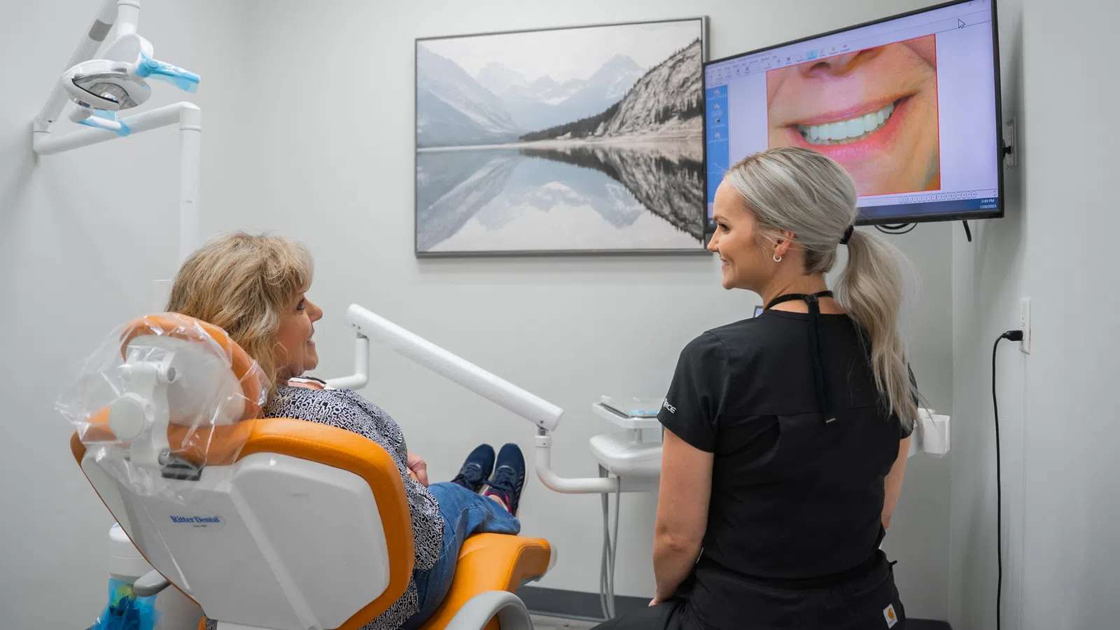 Dentist explaining dental X-ray image of teeth to female patient in modern dental clinic room