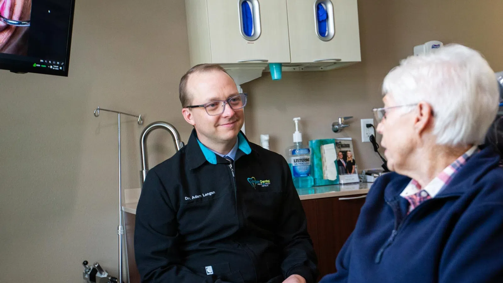 A dentist consults with an elderly patient in a modern dental office, emphasizing patient care and comfort.