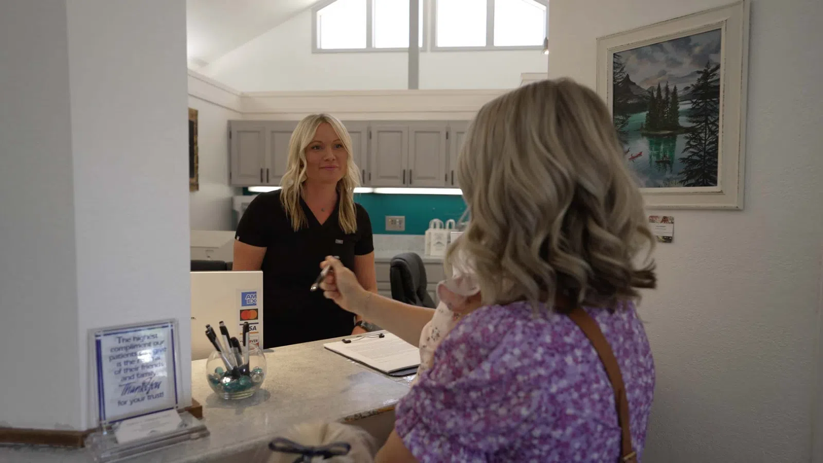 Woman at reception desk handing over keys to a female receptionist in a modern office setting