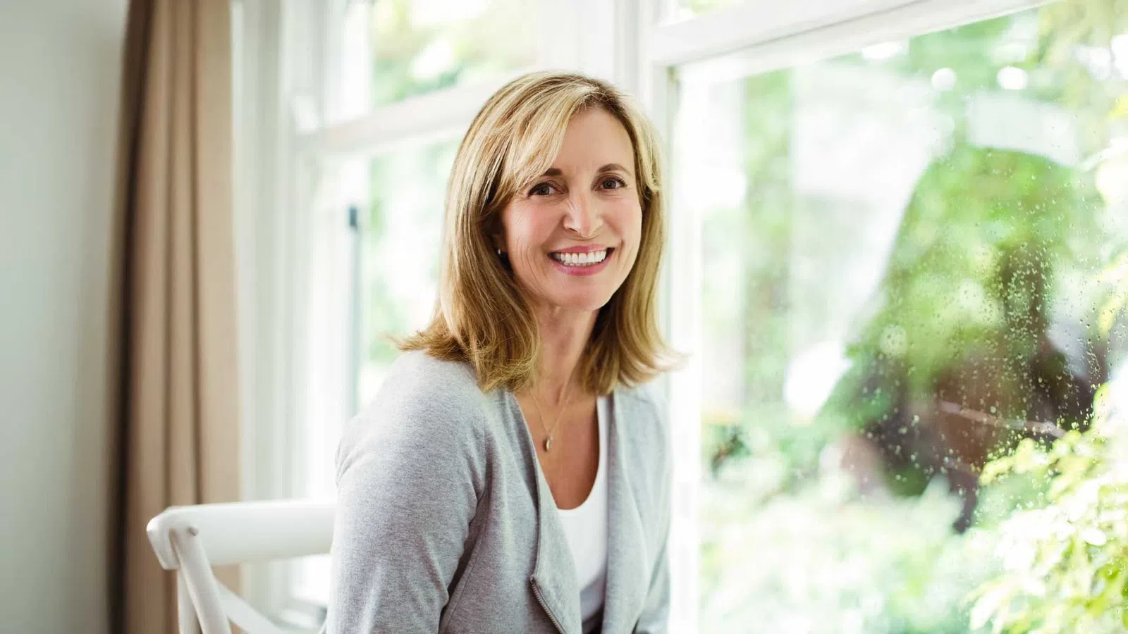 a woman smiling in front of a window