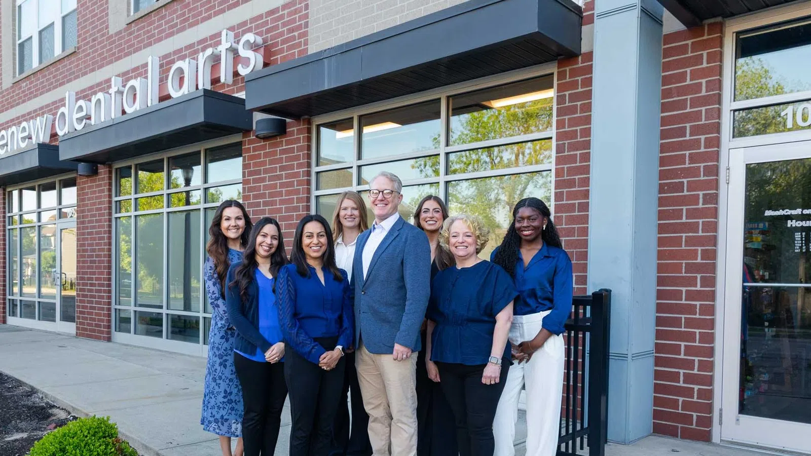 Group of dental professionals standing outside Renew Dental Arts office smiling at camera