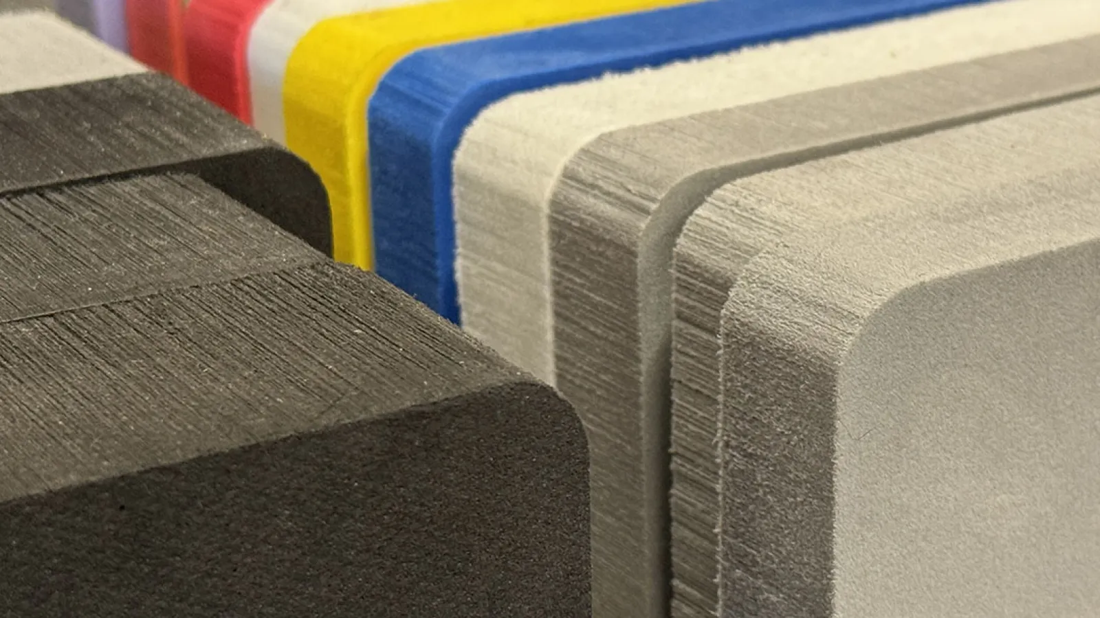 Close-up of stacked colorful foam sheets with rounded edges showing texture and layers.