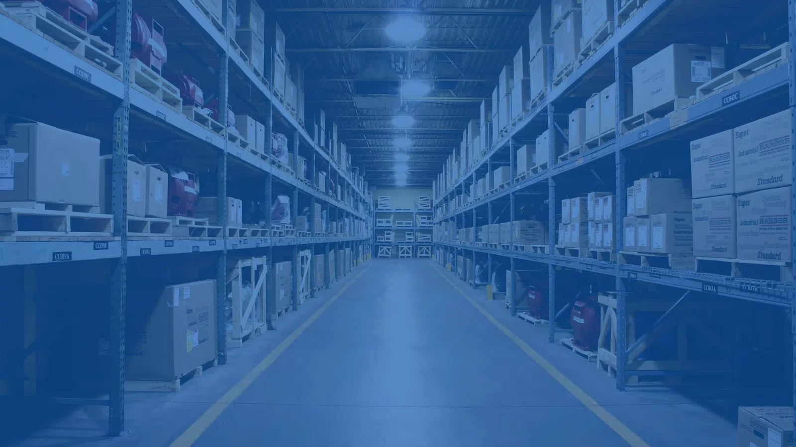 Wide aisle in a large warehouse with tall metal shelves stocked with boxes and packages under bright lighting