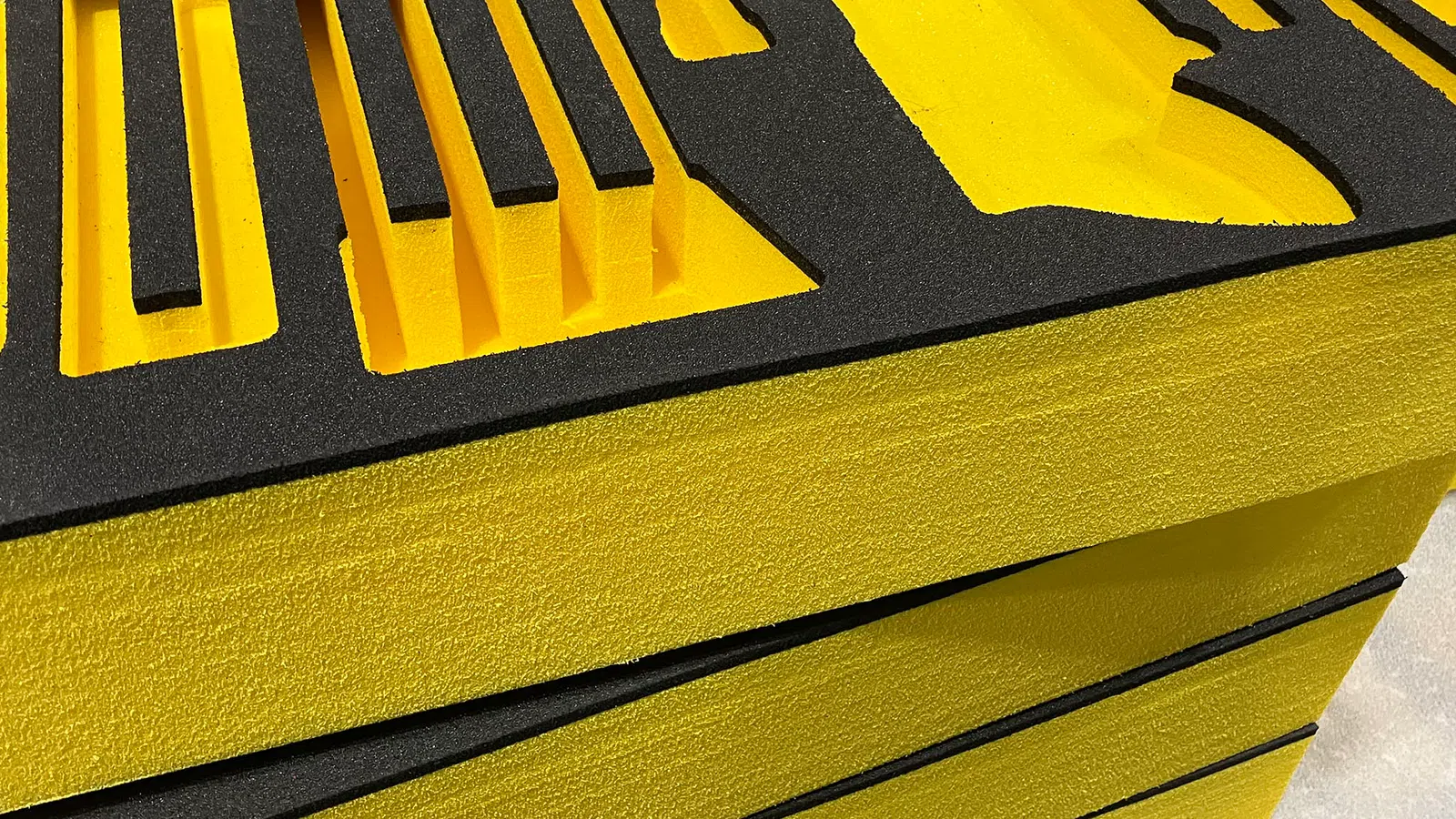 Close-up of black and yellow foam tool organizer with multiple tool-shaped cutouts stacked on a table.