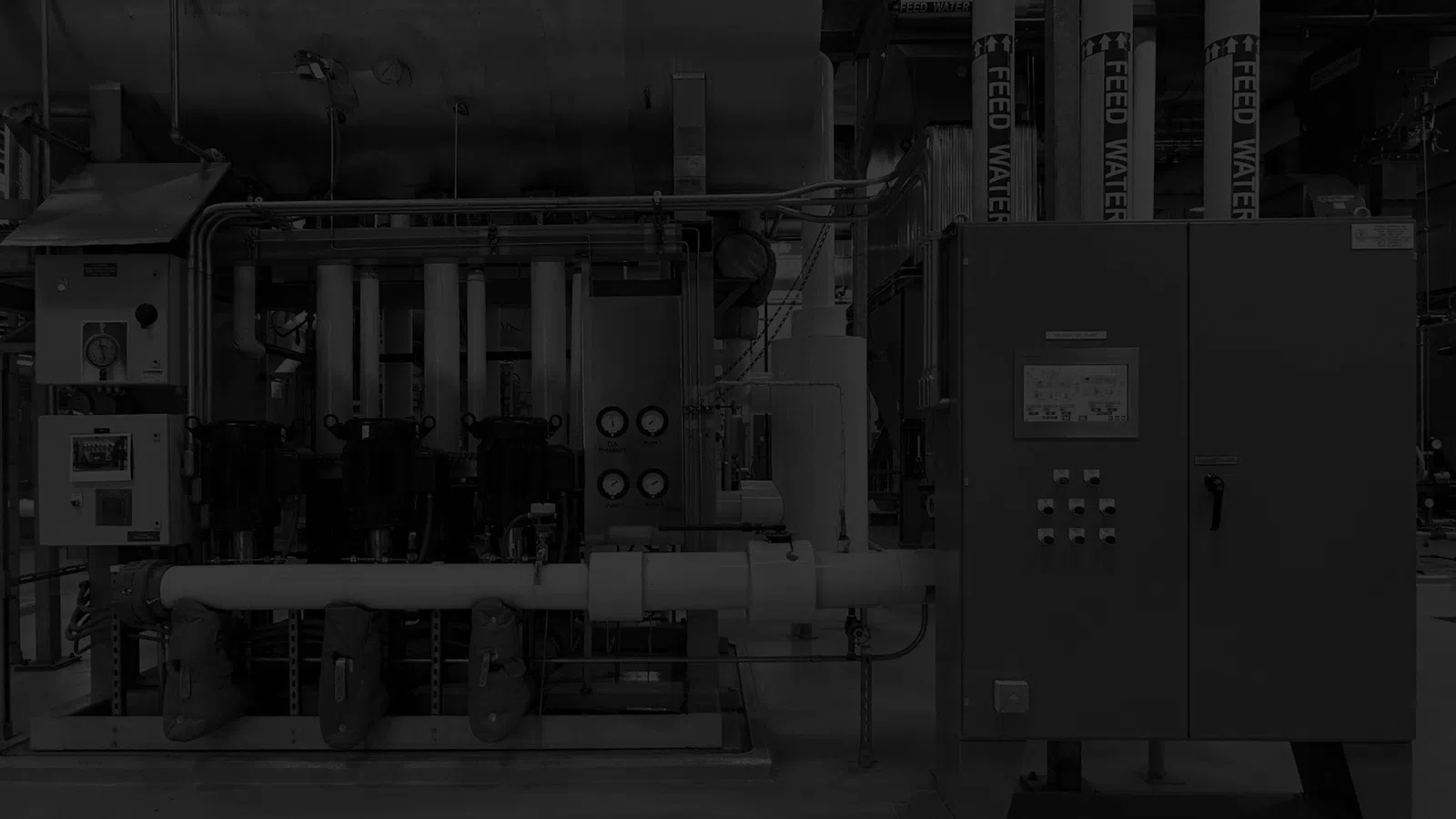 Industrial machinery with control panels, pipes, and gauges in a factory setting for processing or manufacturing.