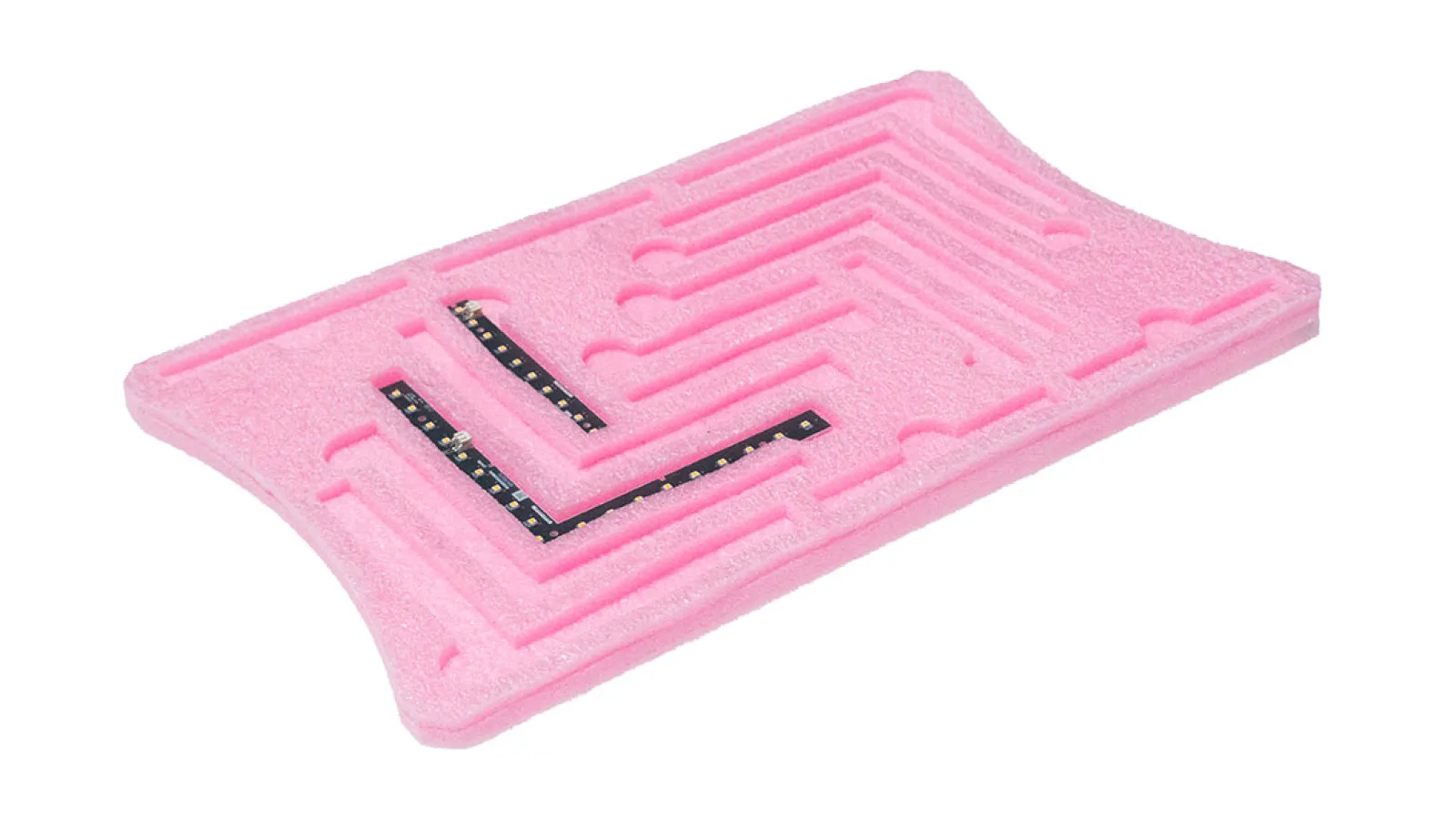 Pink foam tray with shaped compartments holding small electronic components and circuit strips.