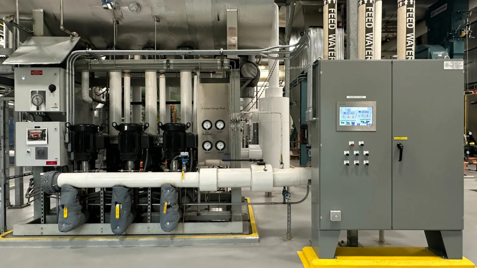 Industrial machinery setup with pipes, gauges, motors, and control panel in a clean factory environment