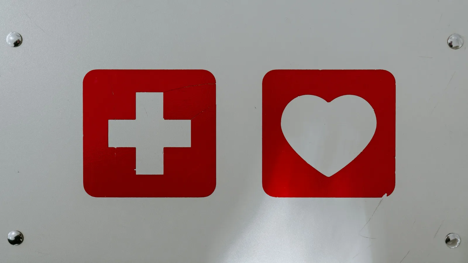Red medical cross and heart symbols on a white background representing health and care.