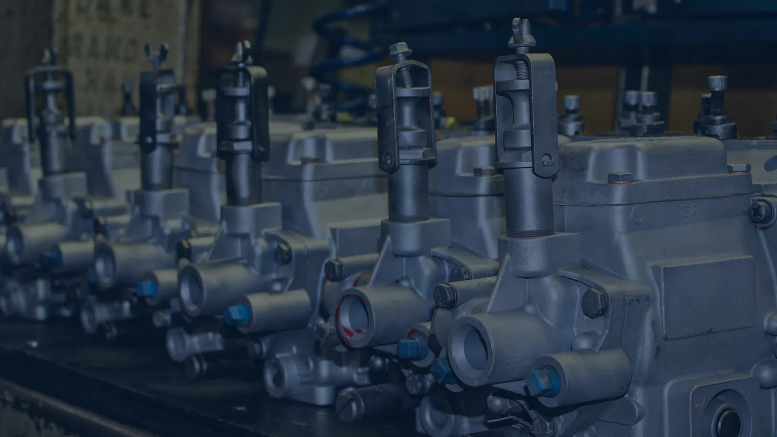 Row of industrial metal valves and mechanical components in a workshop setting.