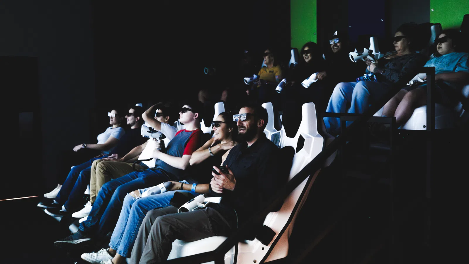 Group of people wearing 3D glasses seated in a theater enjoying an immersive virtual reality experience.