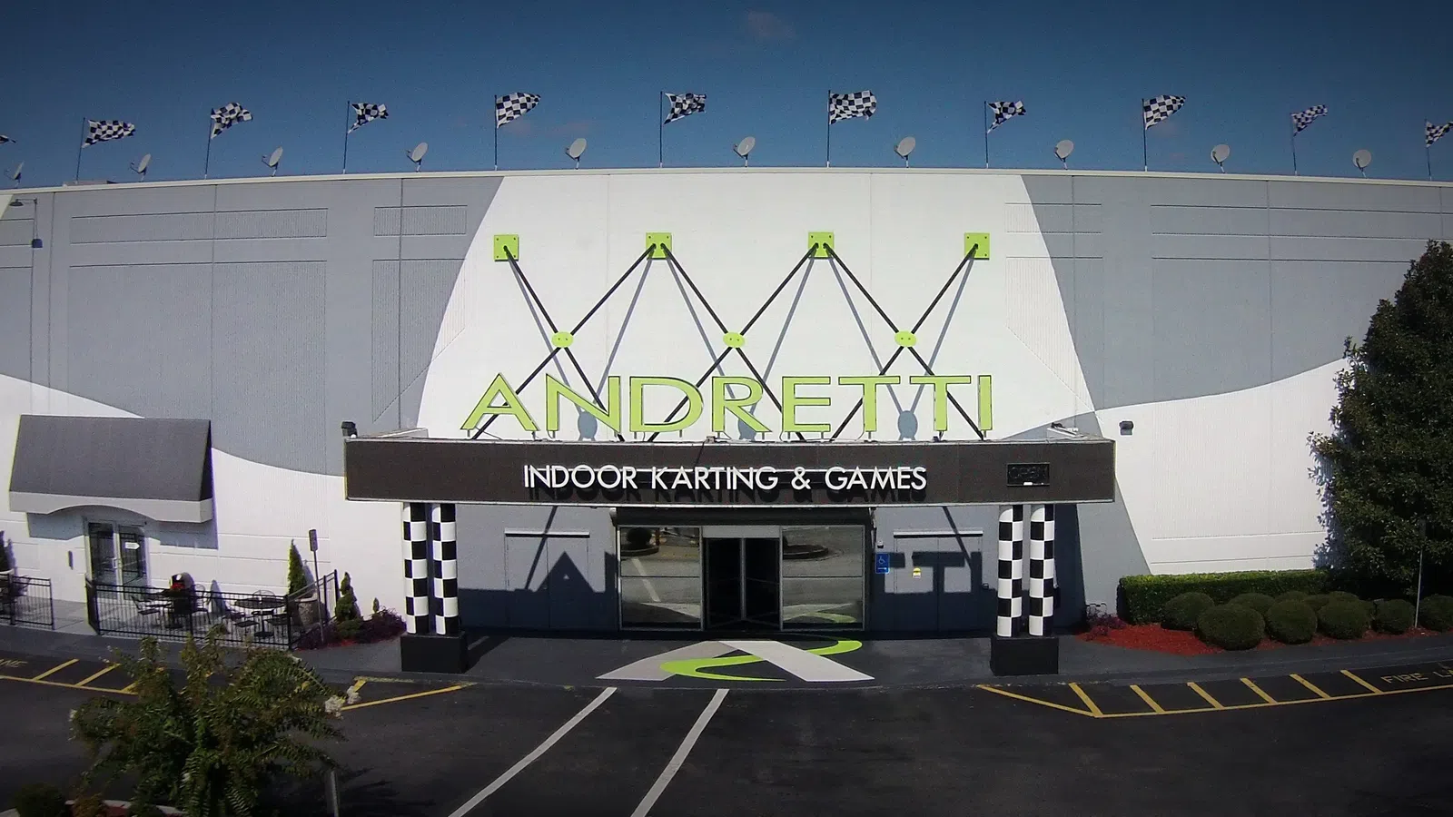 Andretti Indoor Karting & Games building exterior with checkered flags and logo on a sunny day.