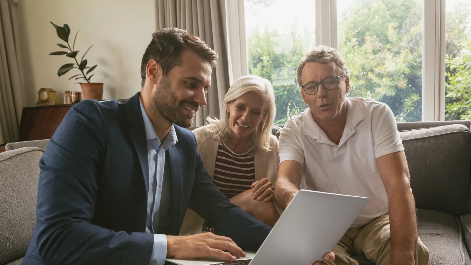 a group of people sitting on a couch looking at a laptop