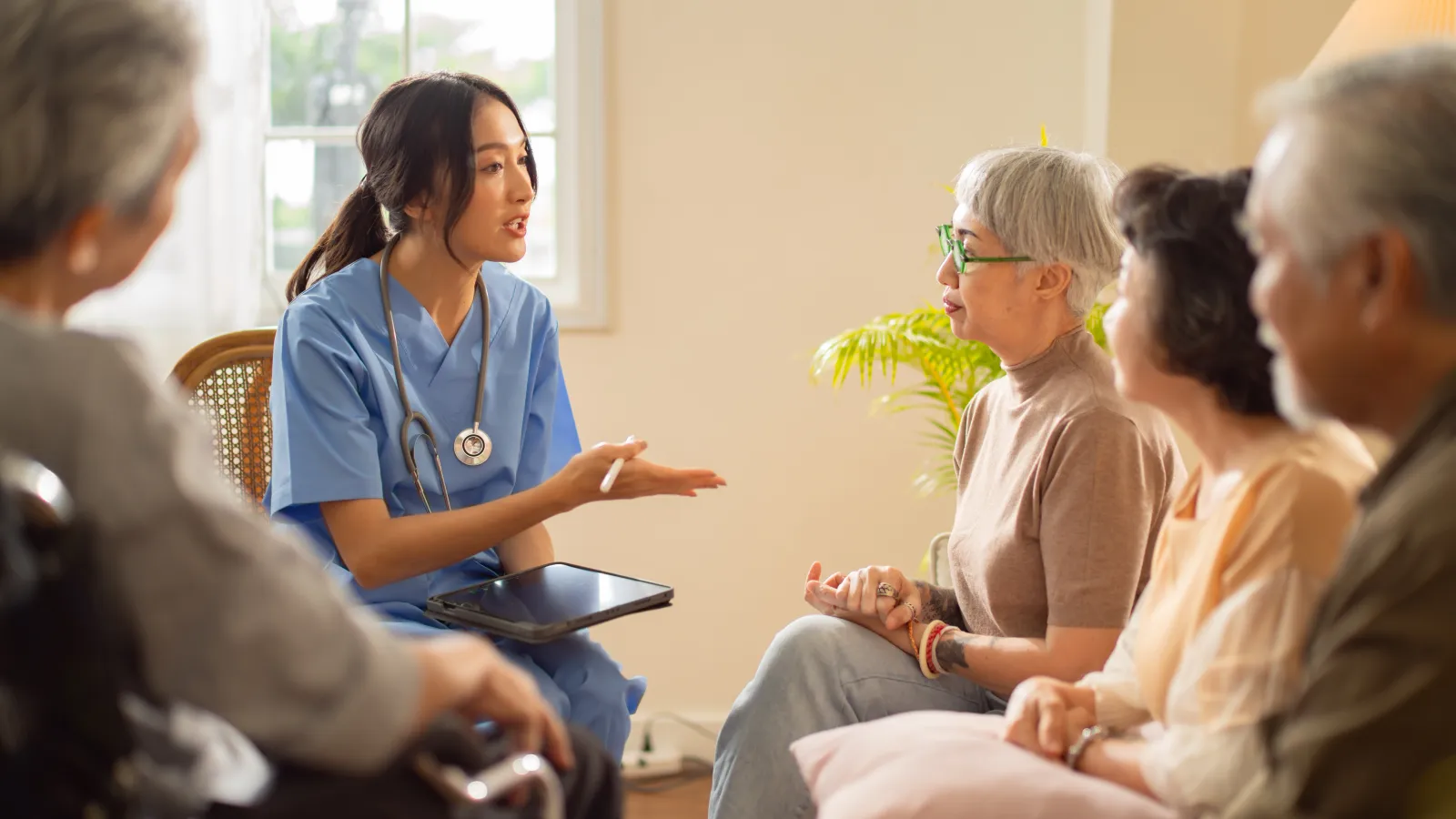 A nurse discusses care options with a group of elderly patients in a warm, inviting room.