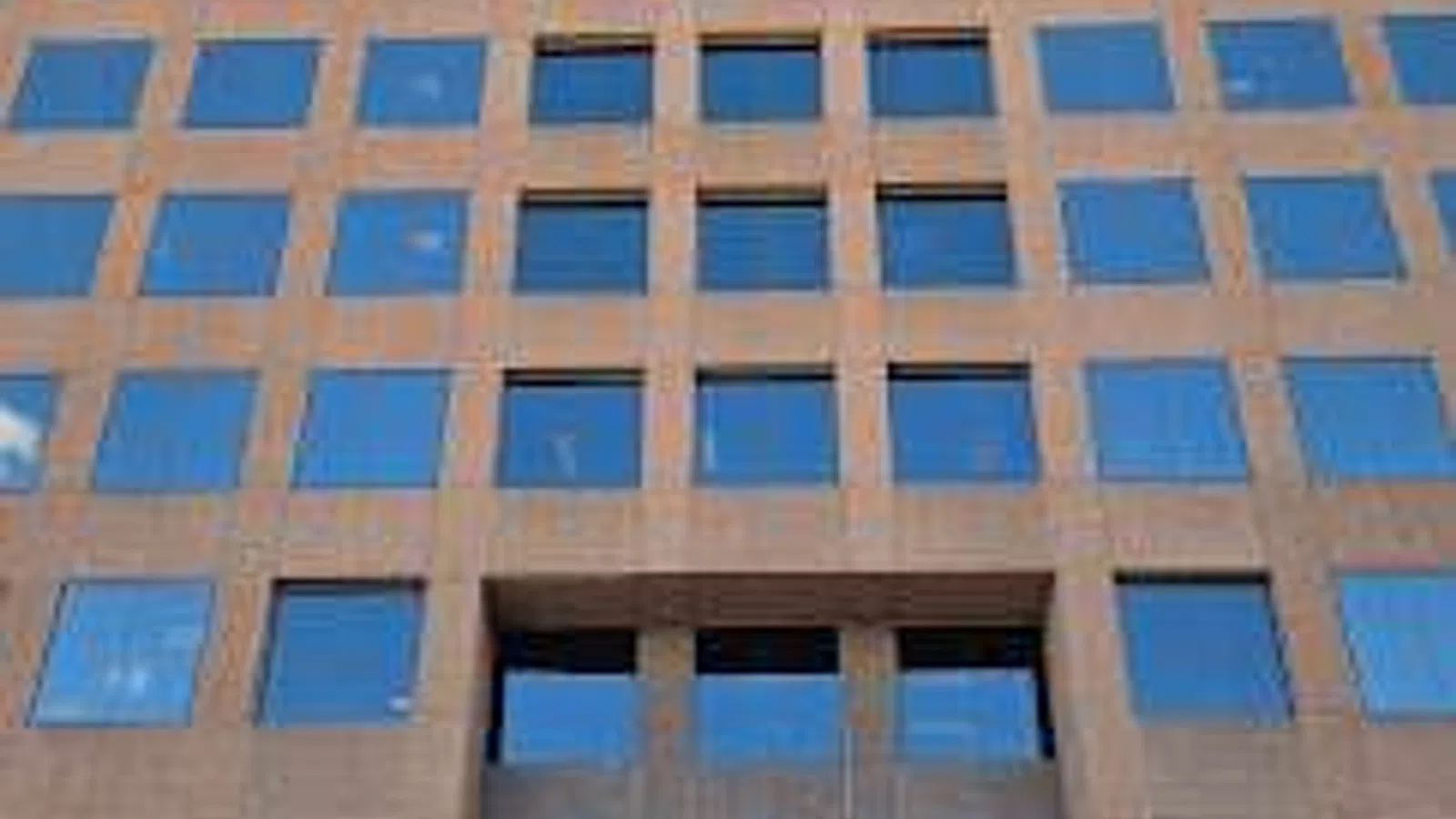 Tall office building with reflective glass windows and a clear blue sky above.