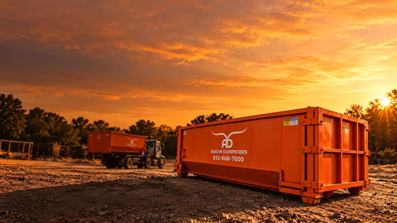 Orange dumpster with Austin Dumpsters logo on dirt ground at sunset with truck and trees in background.