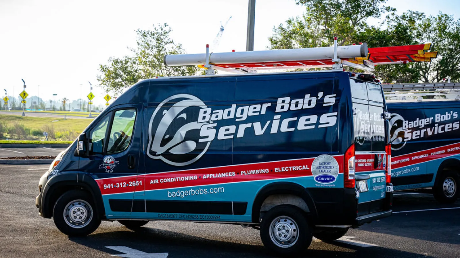 Two men discussing an air conditioning unit in a well-maintained yard, with a woman relaxing nearby.