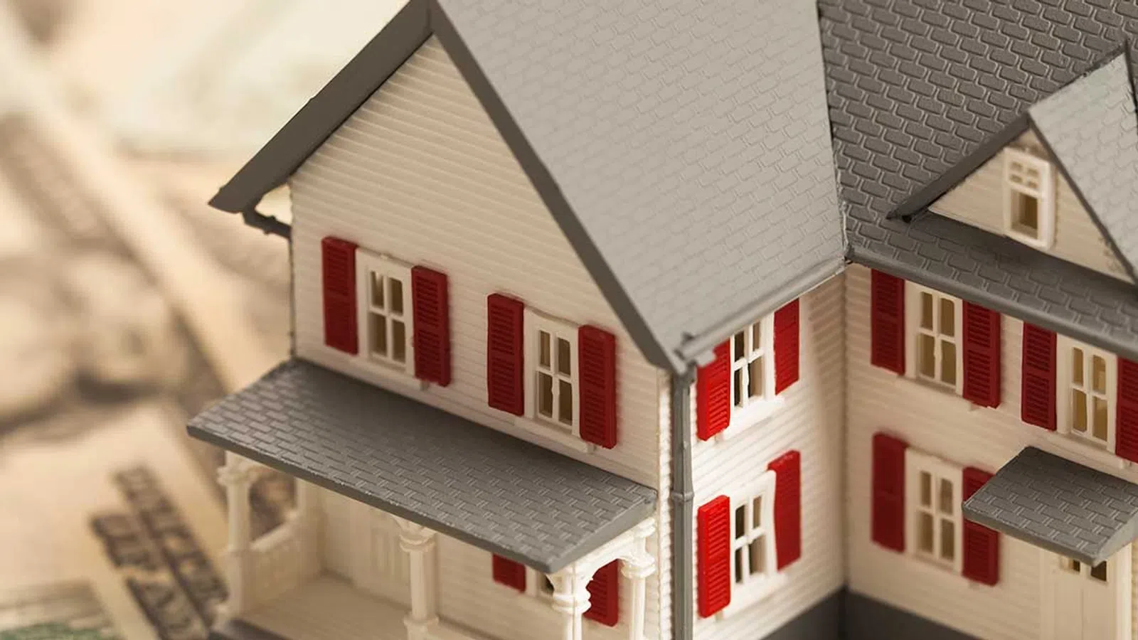Model house on top of US dollar bills symbolizing real estate investment and home financing concepts.