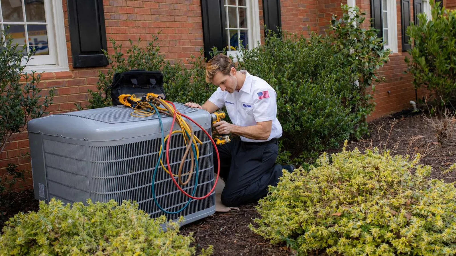 Technician performing a tune-up on an air conditioner during a maintenance visit.