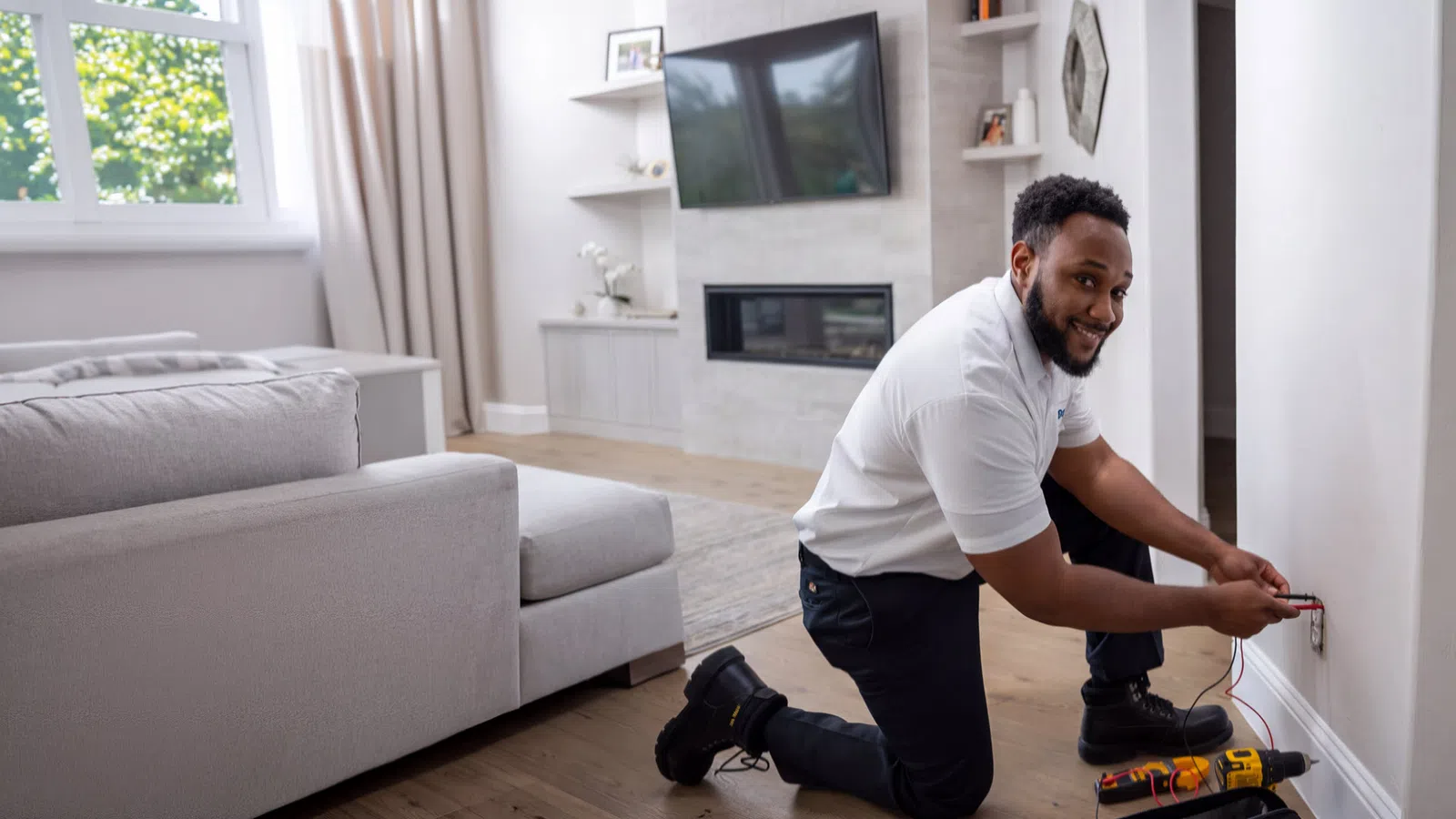 Electrician testing a wall outlet in a residential living room