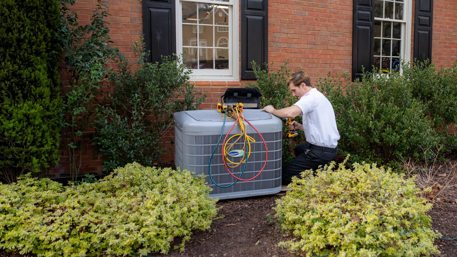 Bardi technician servicing an outdoor HVAC system at a residential home