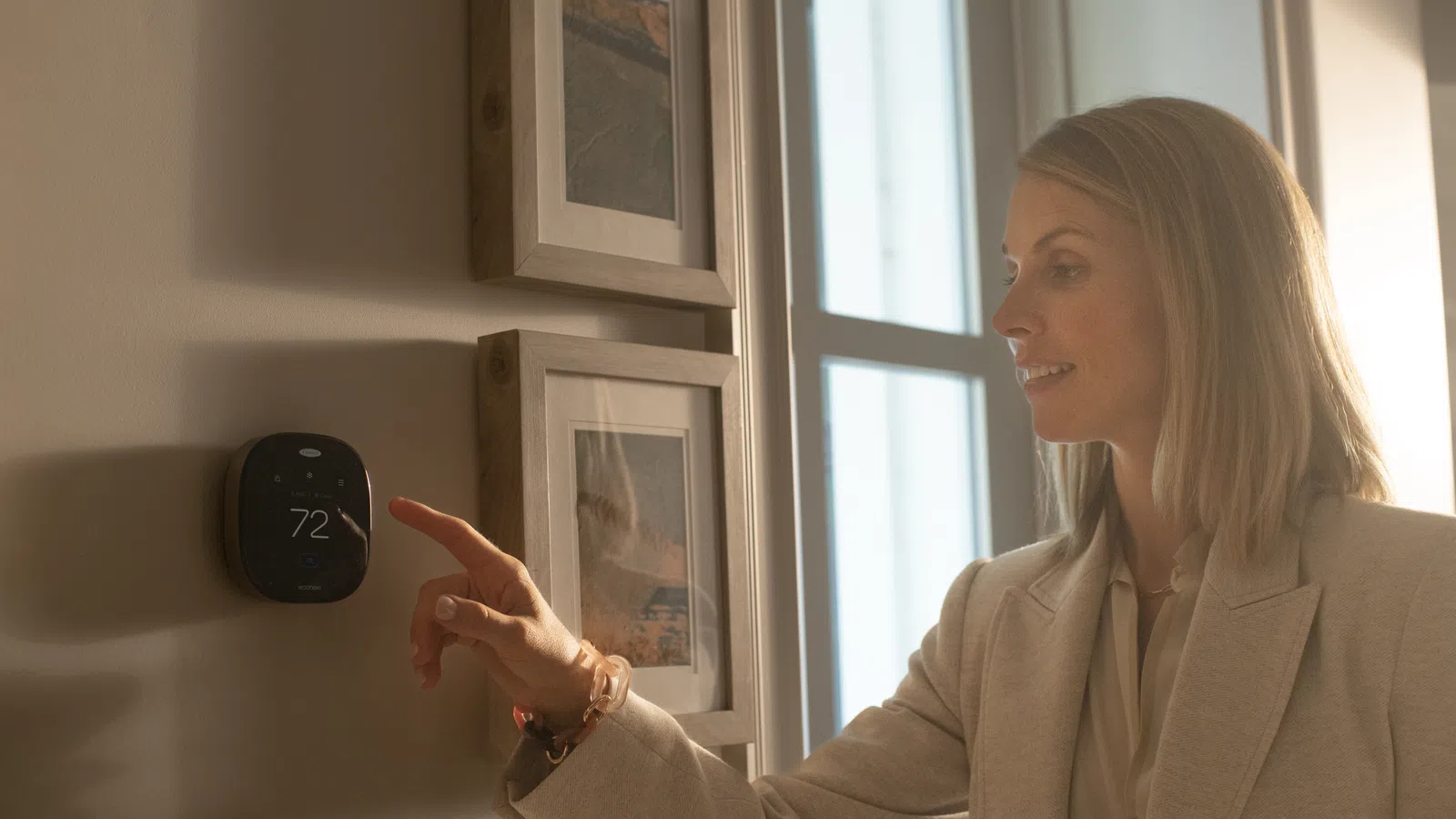 a woman adjusting the thermostat in her home