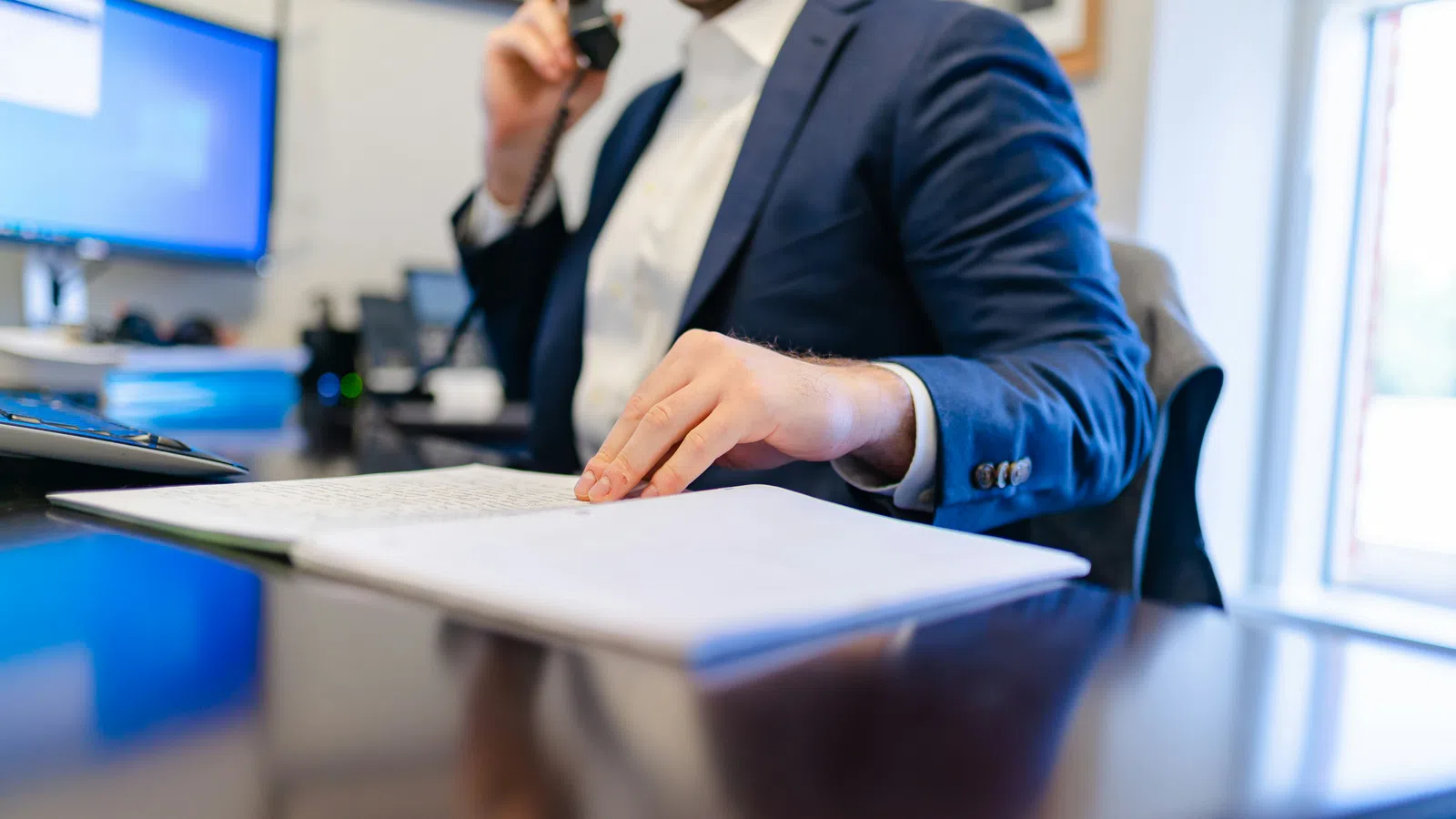 a man in a suit sitting at a desk with a phone