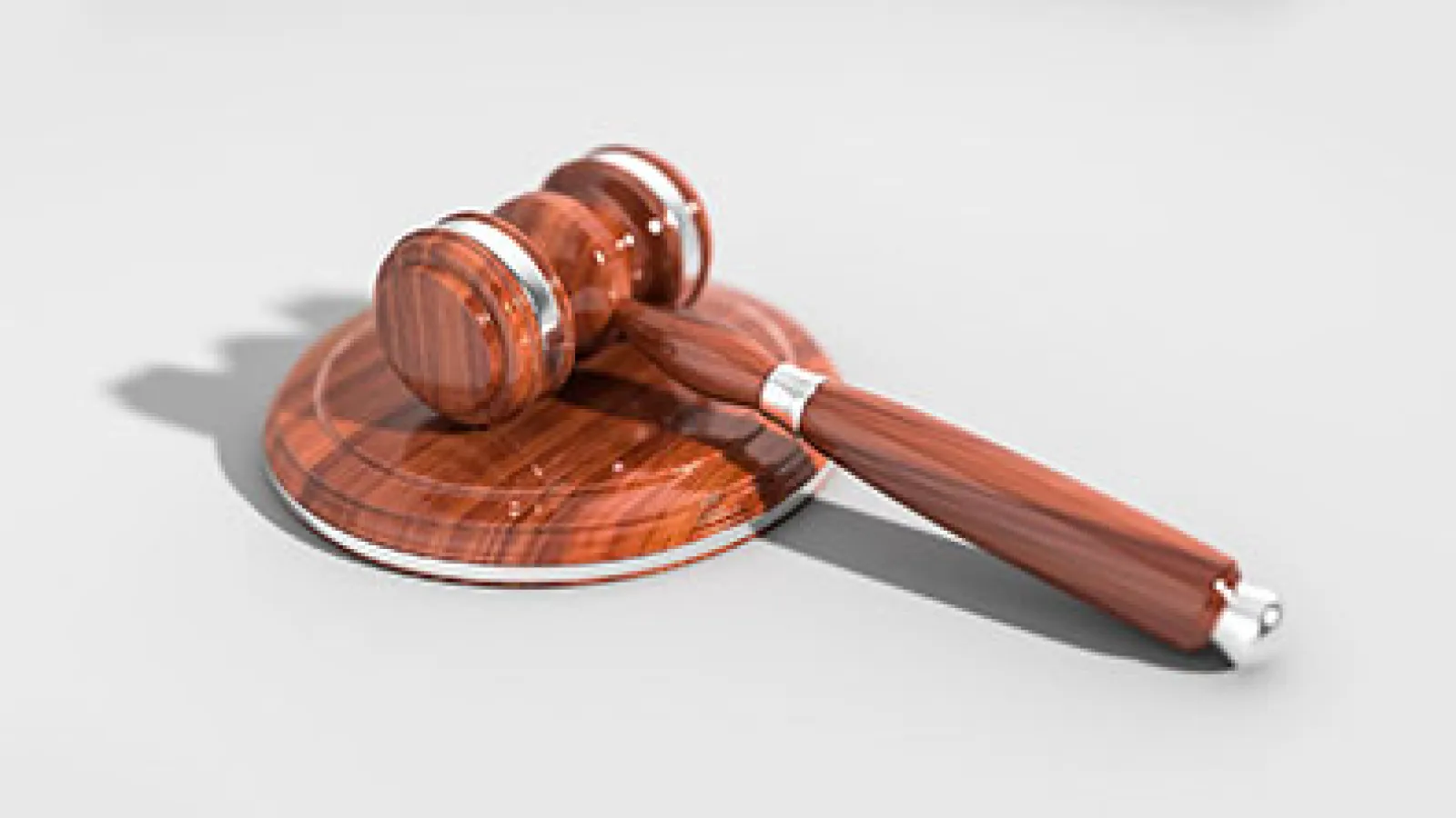 Wooden judge gavel and sound block on white background symbolizing law and justice.