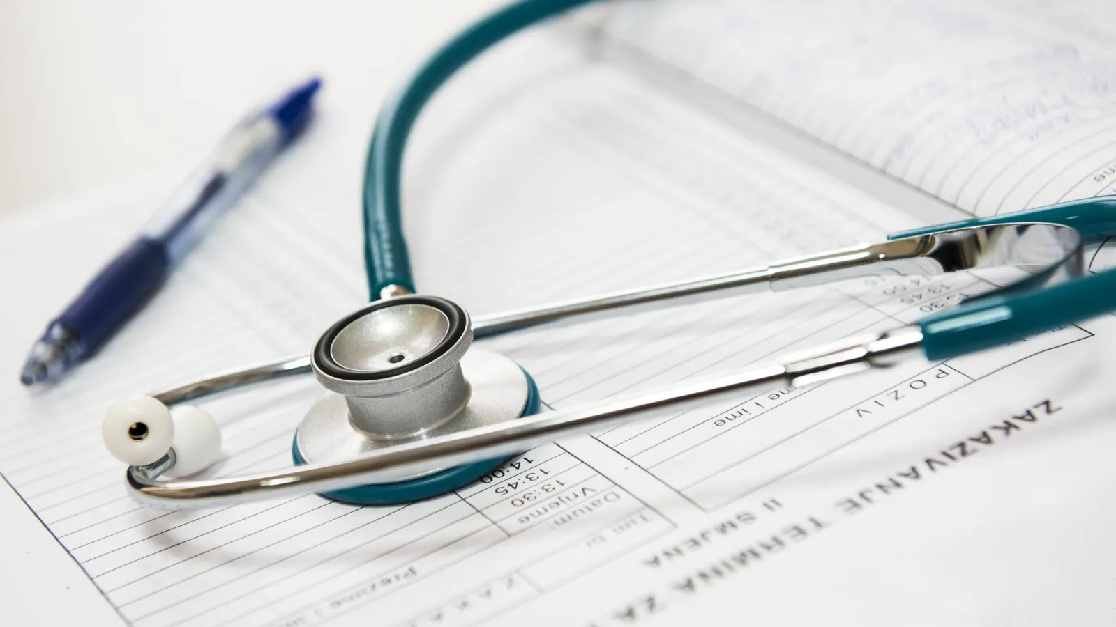 Stethoscope and pen resting on medical forms highlighting health examination details and patient data.