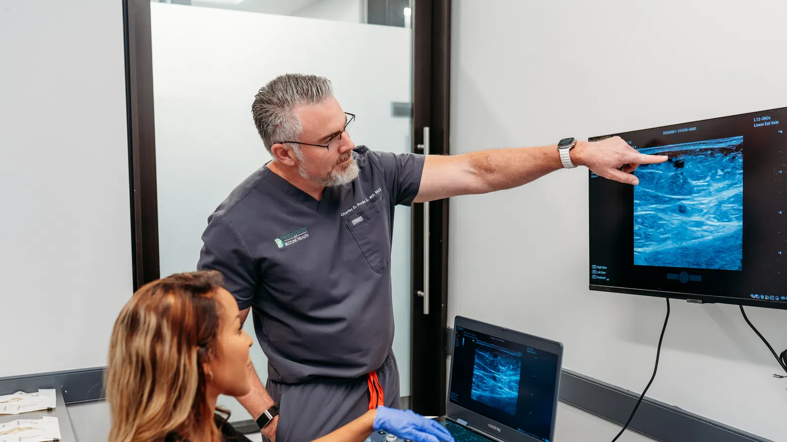 Doctor explaining ultrasound scan results to female patient in a medical examination room.