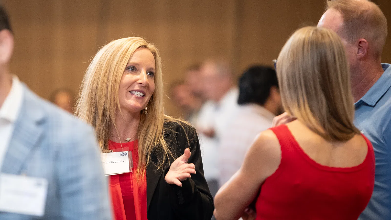 Professional networking event with people engaged in conversation wearing business casual attire indoors.
