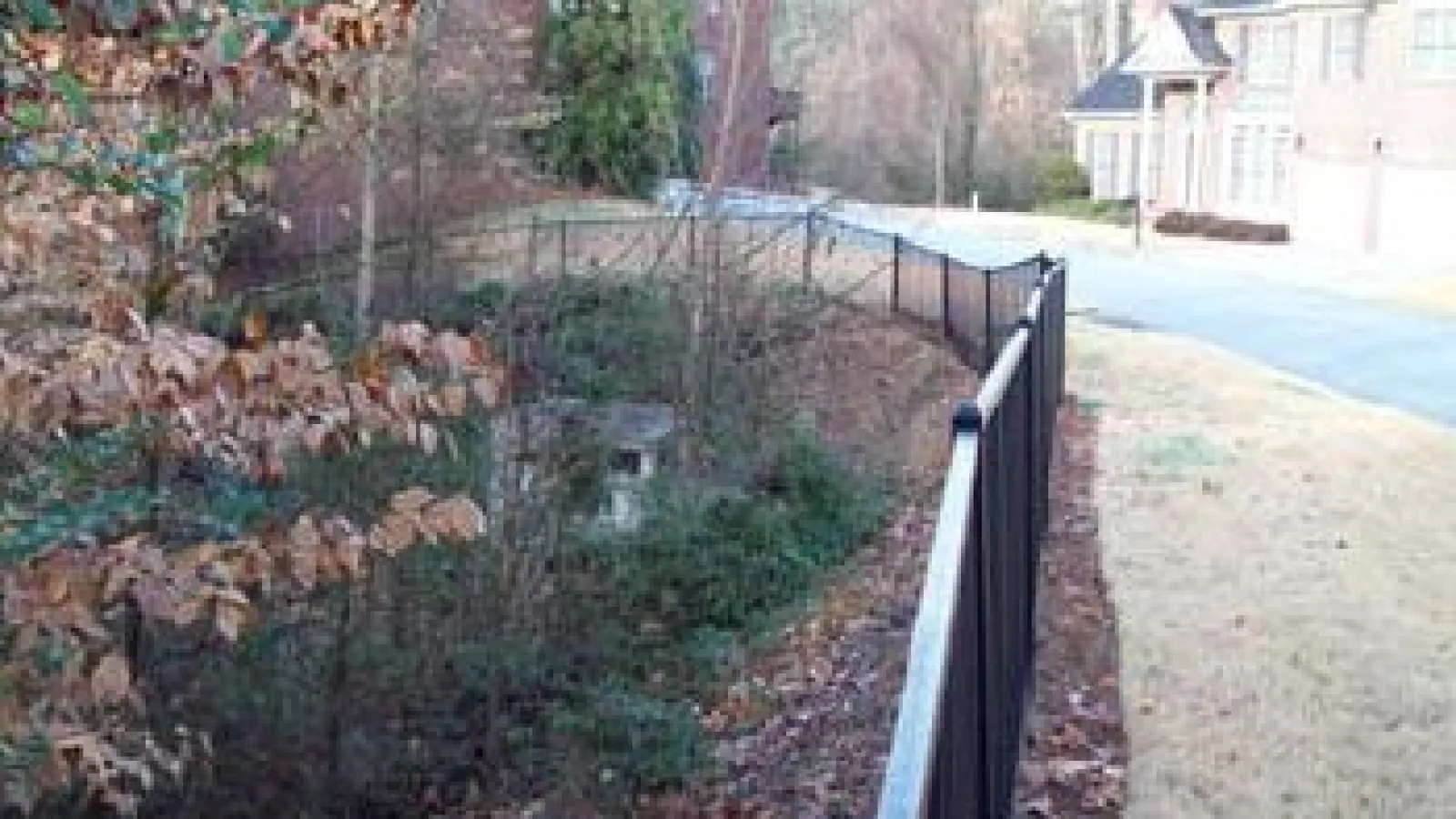 a fenced off path with a metal gate and a house in the background