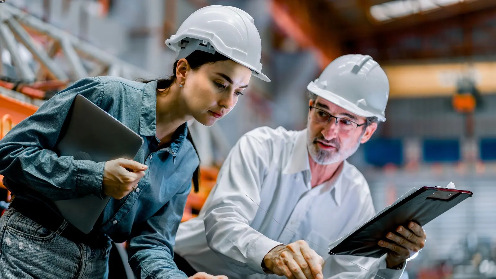 a few people wearing hard hats looking at a laptop